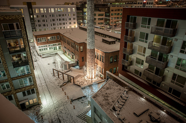 View of an apartment courtyard front he roof. The courtyard is covered in snow.
